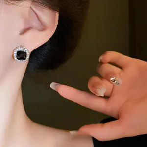 Detail view of square silver-plated earring with clear rhinestones and black center stone
