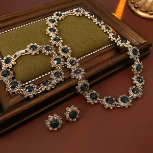 Vintage palace style jewelry set with blue rhinestone flowers on wooden frame.