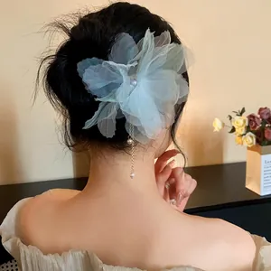 Macro view of a pale green chiffon flower hair pin featuring an elegant pearl tassel