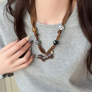 Handmade brown ribbon necklace with dachshund pendant and quirky patterned beads.