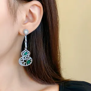Detail view of elegant Chinese style hollow gourd drop earrings with green emerald gems