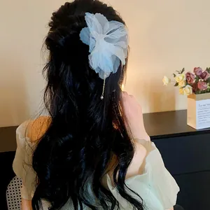Detail view of a large white chiffon flower hair pin with a delicate pearl tassel