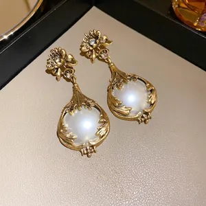 Vue rapprochée de boucles d'oreilles vintage avec fleurs, perles blanches et fini doré