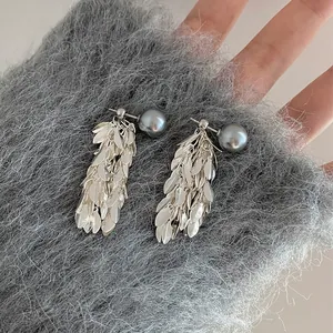 Close-up of French style pearl tassel earrings with metallic silver leaf fringe details