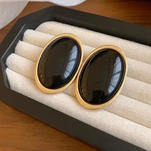 Retro oval resin earrings with matte gold border on a white jewelry tray display.