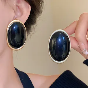 Detailed view of vintage elliptical resin earrings with matte gold borders on model.