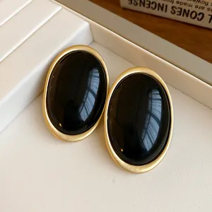 Elegant vintage oval black resin stud earrings with a matte gold-tone frame finish