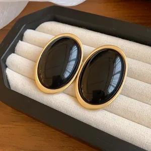Macro view of vintage black oval resin earrings with a minimalist gold metal frame