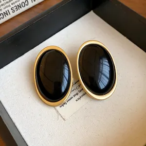 Detail view of vintage oval resin earrings with gold frame and black stone inlay.