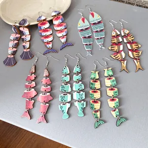 Orecchini pendenti etnici in legno a forma di pesce con motivi colorati vari.