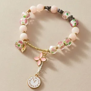 Detailed view of colorful lampwork glass bead bracelet with pink flower and clock charms