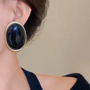 Detailed close-up shot of vintage oval black resin earrings with a gold frame design