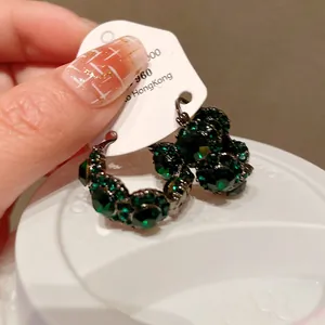 Nahaufnahme von smaragdgrünen Strass-Creolen in U-Form im Vintage-Stil auf weißem Grund.