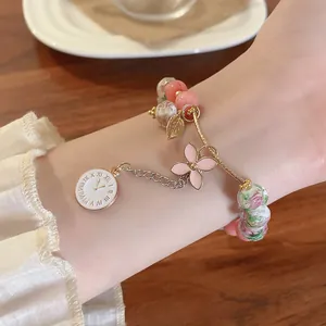 Detailed macro view of an elegant glass bead bracelet featuring a pink flower and clock charm