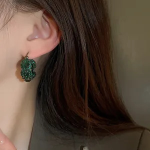 Detailaufnahme von eleganten Vintage U-Ohrringen mit funkelnden grünen Strasssteinen