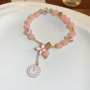 Close-up of pink glass bead bracelet featuring elegant flower and clock dial charms