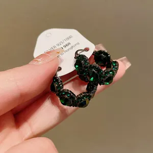Nahaufnahme von Vintage U-Form Ohrringen mit smaragdgrünen Kristallen auf Karte
