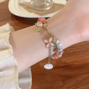 Detailed view of an elegant glass bead bracelet featuring pink floral and clock charms