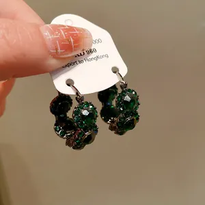 Nahaufnahme von vintage Ohrringen mit grünen Strasssteinen in U-Form auf Karte.