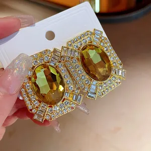 Detailed view of luxury gold square earrings with amber crystals and rhinestones
