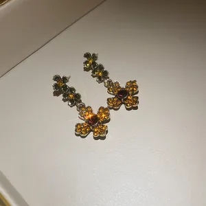 Detail shot of vintage flower drop earrings with yellow and purple rhinestones