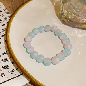 Close-up view of pink and blue gradient glass beaded bracelet on a ceramic plate