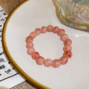 Close-up of pink crackle glass bead bracelet with gold spacers in oriental style