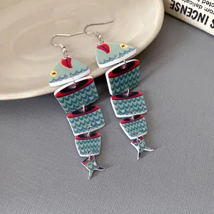 Dettaglio macro di orecchini a forma di pesce in legno stile etnico con stampa a squame.
