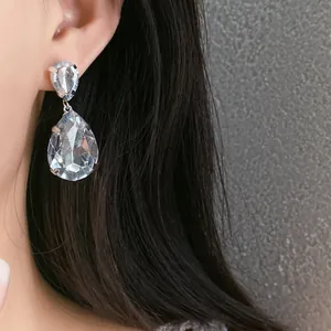 Close-up view of elegant waterdrop crystal earrings worn on a model's ear for jewelry display