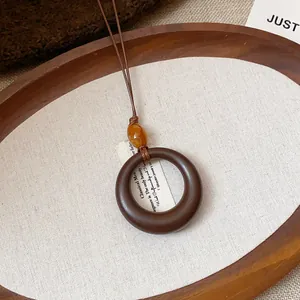 Vista dettagliata di una collana con ciondolo ad anello in resina su vassoio in legno