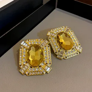 Detail of vintage palace style earrings with yellow oval crystal and clear rhinestones