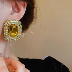 Close-up of vintage French style gold-tone earrings with amber crystal and rhinestones.