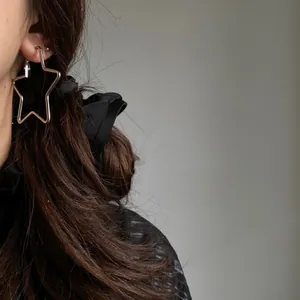 Detailed close-up showing a silver star-shaped hoop earring worn on a female ear