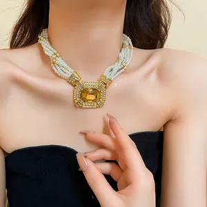 Detailed view of a French vintage pearl necklace with square rhinestone pendant on model.