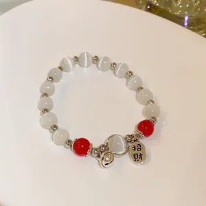 Elegant handmade beaded bracelet with white cat's eye stones and a wealth charm