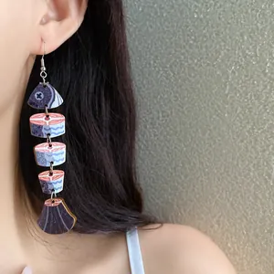 Primo piano di orecchini pendenti in legno a forma di pesce indossati da una modella asiatica