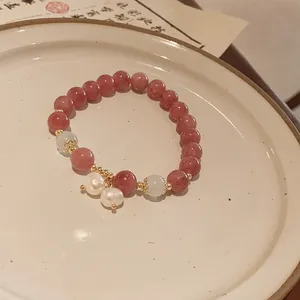 Detailed macro view of a strawberry quartz beaded bracelet with white pearl charms.