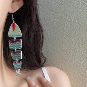 Vista dettagliata di una modella che indossa orecchini etnici in legno a forma di pesce