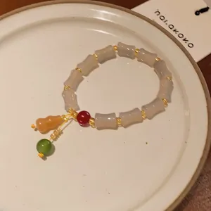 Close-up of a handcrafted New Chinese style bracelet with bamboo-shaped beads and charms