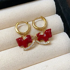 Close-up of red enamel horse earrings with gold plating and sparkling zircon stones