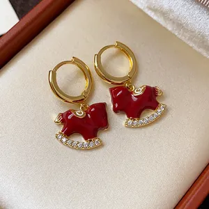 Detailed macro shot of gold-plated rocking horse earrings with red enamel and CZ stones