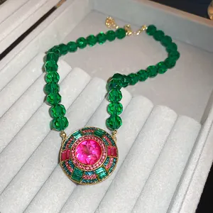 Détail d'un collier de style vintage avec des perles vertes et un pendentif rose.