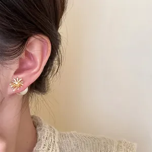 Dettaglio di eleganti orecchini a fiore placcati oro con zirconi e dettagli in perle
