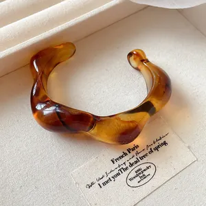 Detailed view of an irregular wide acrylic bangle with stylish amber smudge texture