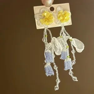 Close-up of delicate chiffon lily of the valley tassel earrings featuring glass beads