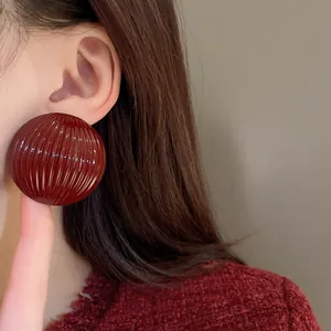 Detailed macro shot of a dark red striped semi-circular metal earring on a model's ear.