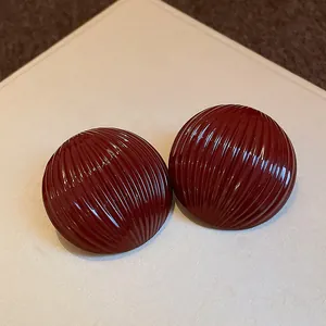 Close-up of deep red striped semi-circular stud earrings with high-gloss finish