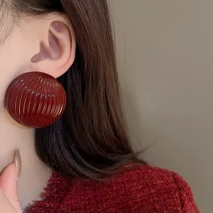 Close-up detail shot of large deep red striped semi-circle stud earrings on model