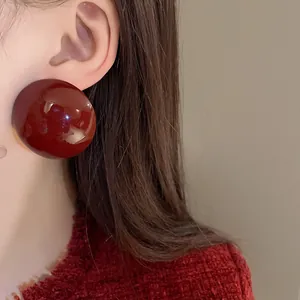 Close-up detailed macro shot of a stylish red semicircular stud earring worn on the ear
