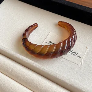 Statement amber resin open bangle with twisted geometric texture and marbled pattern finish